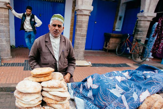 Elderly man selling traditional Moroccan bread at an Essaouira street market.