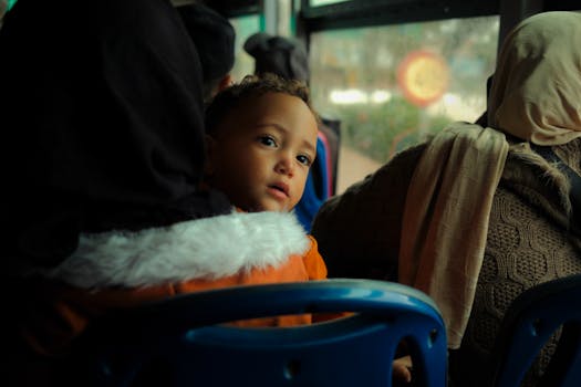 A young child gazes thoughtfully out the window of a bus in Morocco, surrounded by adults.