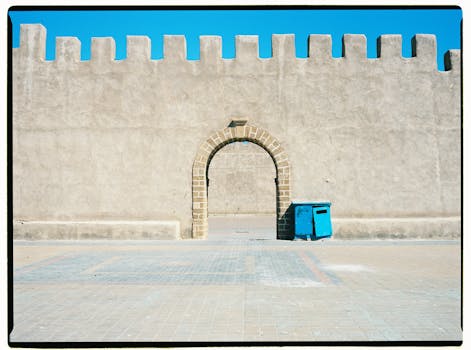 Stone archway in historic Essaouira wall under bright blue sky. Minimalist architectural scene.