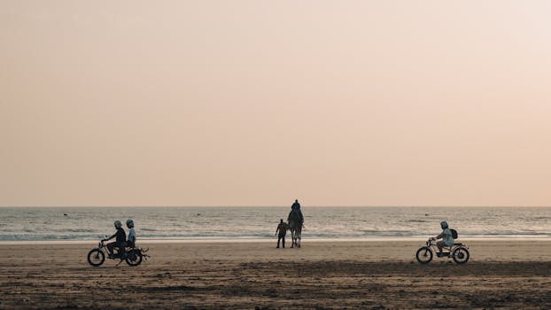 A serene scene of camels and motorbikes on Essaouira beach during sunset, capturing Morocco's coastal beauty.