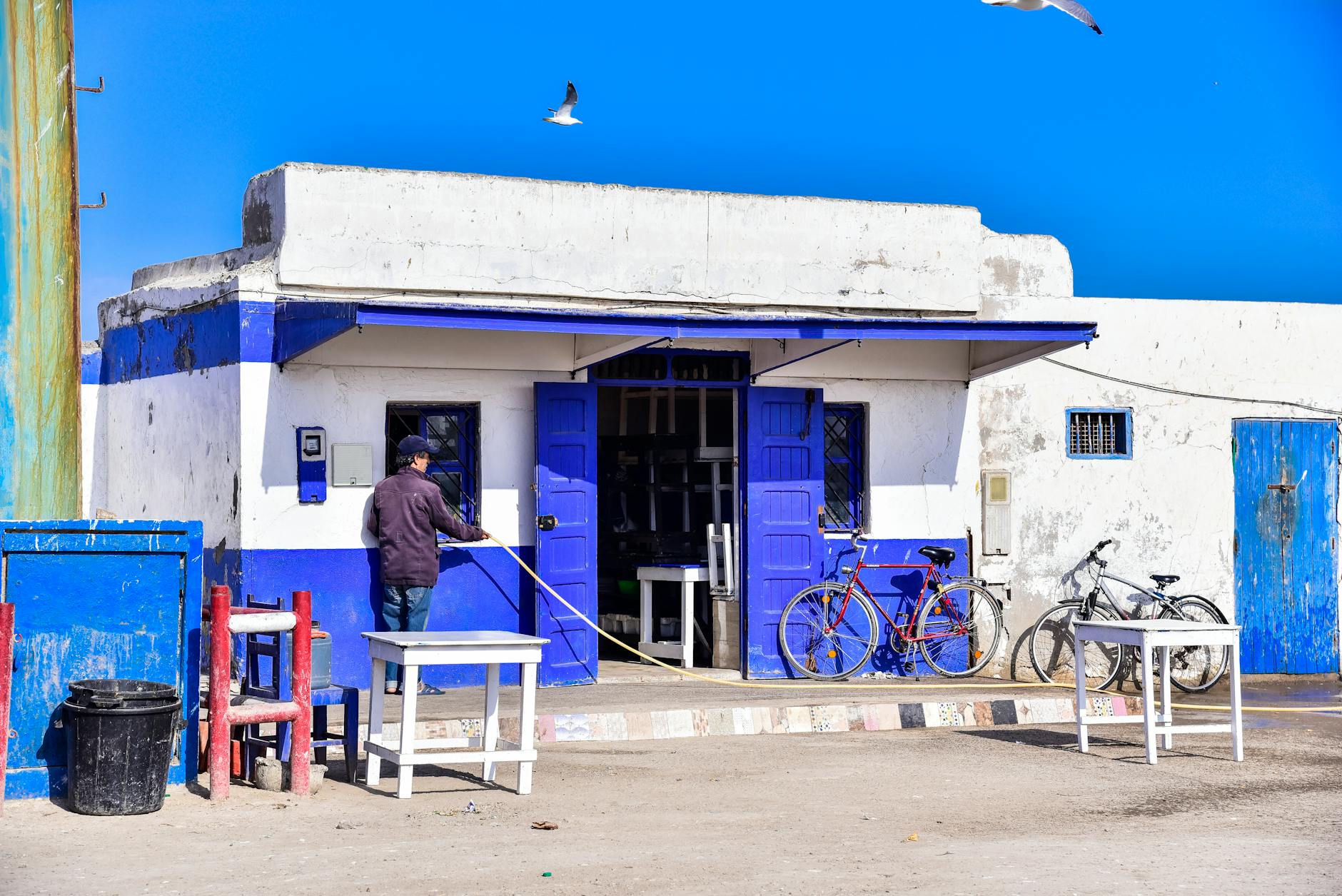 A vibrant blue and white building with bicycles in Essaouira, Morocco on a sunny day.