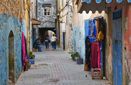 Charming alley in Essaouira with vibrant textiles and historic architecture.